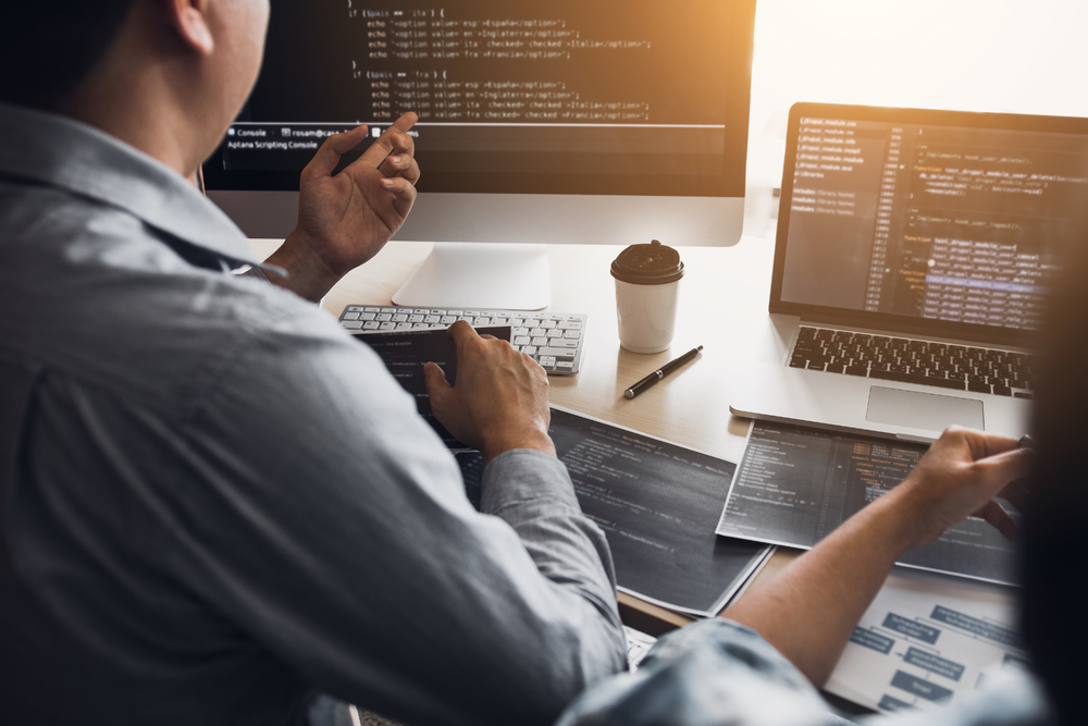 兩名軟件開發人員正在使用計算機與辦公桌上的合作伙伴一起工作